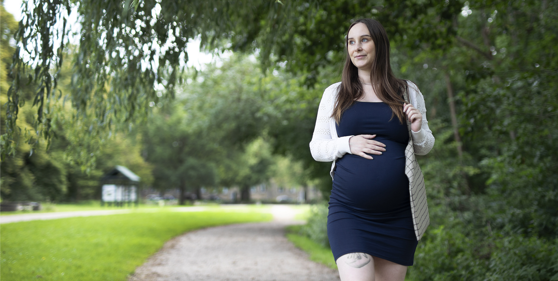 Billede af gravid kvinde, der går tur med den ene hånd på maven.